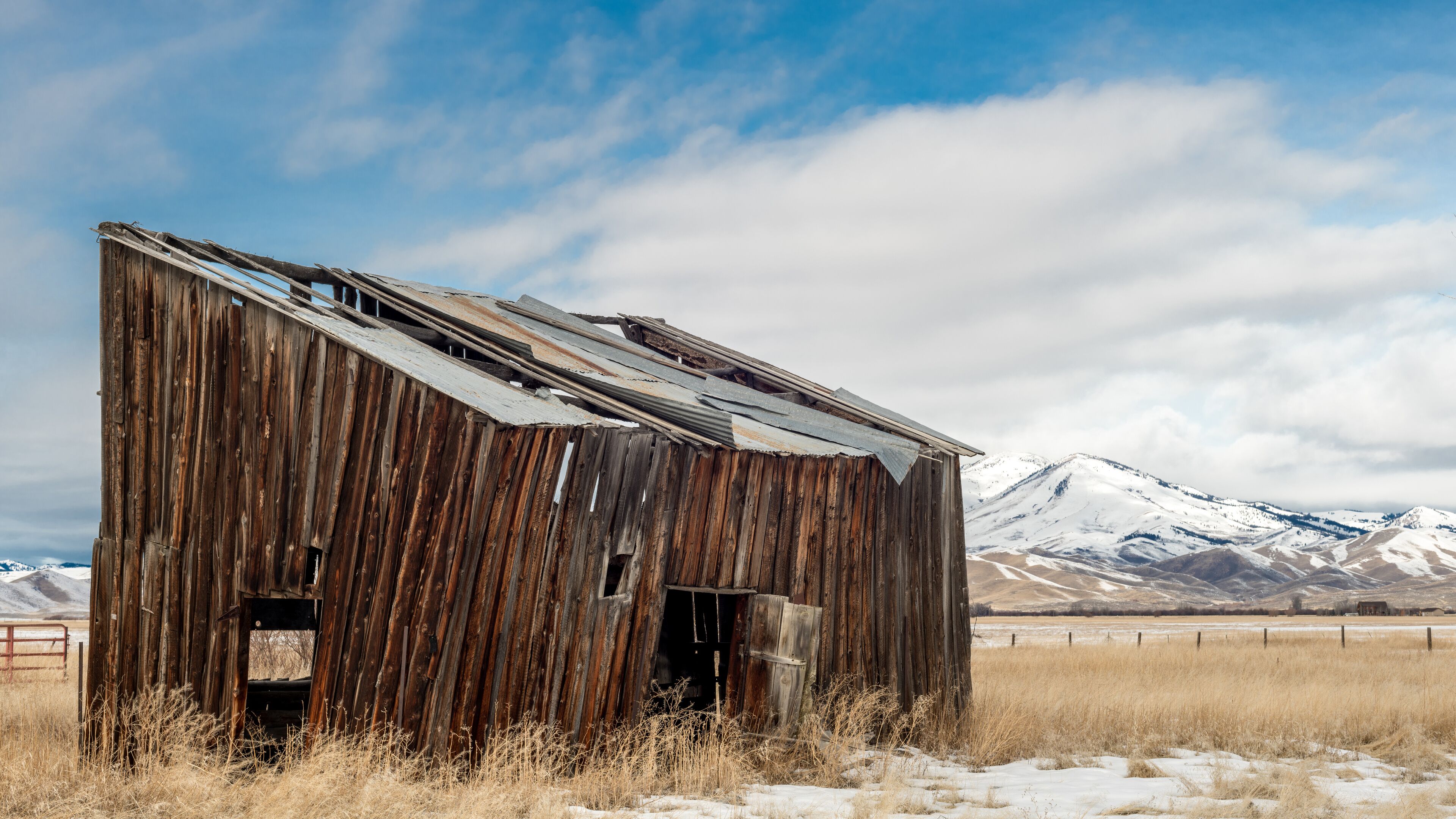 Farmers out building with snow covered mountains and cloudy sky