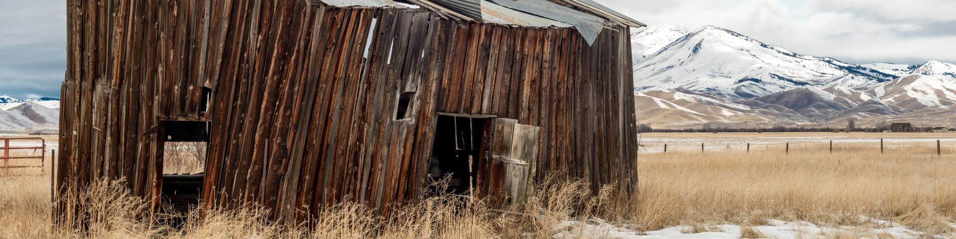 Farmers out building with snow covered mountains and cloudy sky
