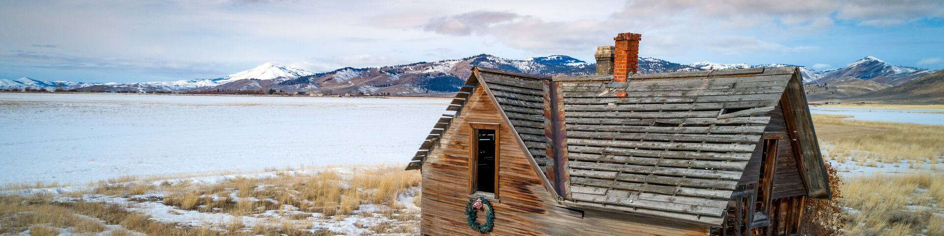 Abandoned farmhouse near Fairfield Idaho with snow in the mountains