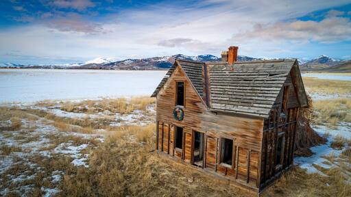 Abandoned farmhouse near Fairfield Idaho with snow in the mountains