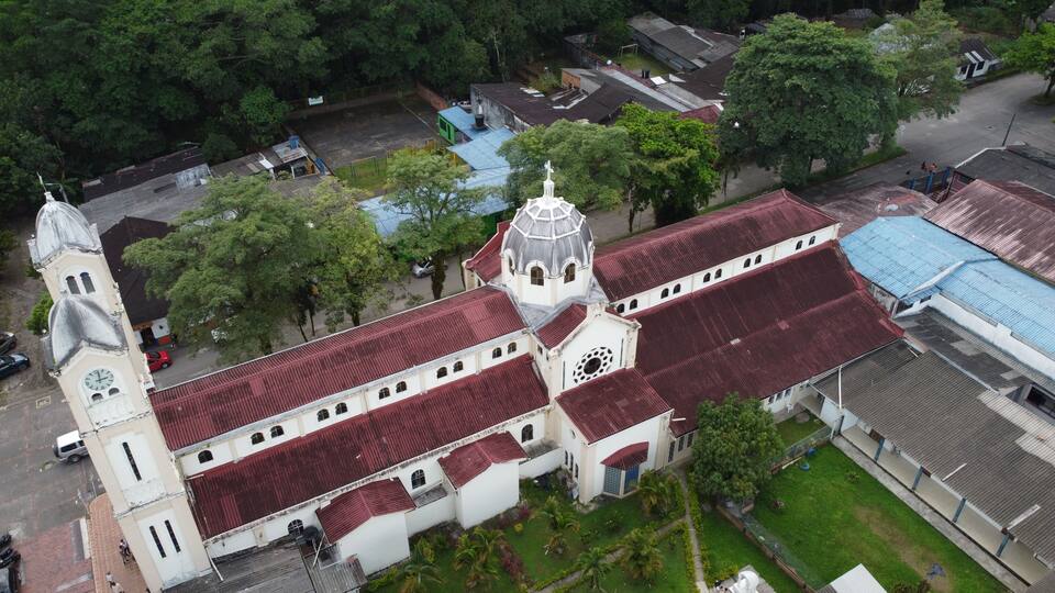 An aerial view of a church with a red roof and a bell tower.