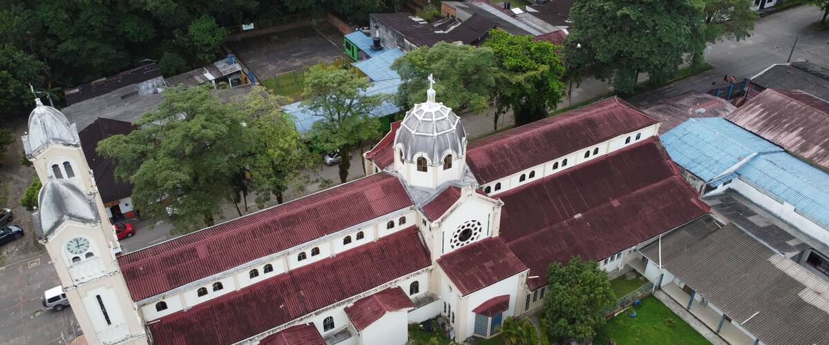 An aerial view of a church with a red roof and a bell tower.