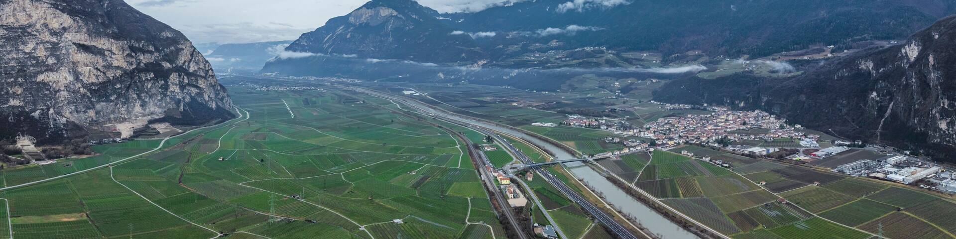 A valley with green fields, a river, and mountains.