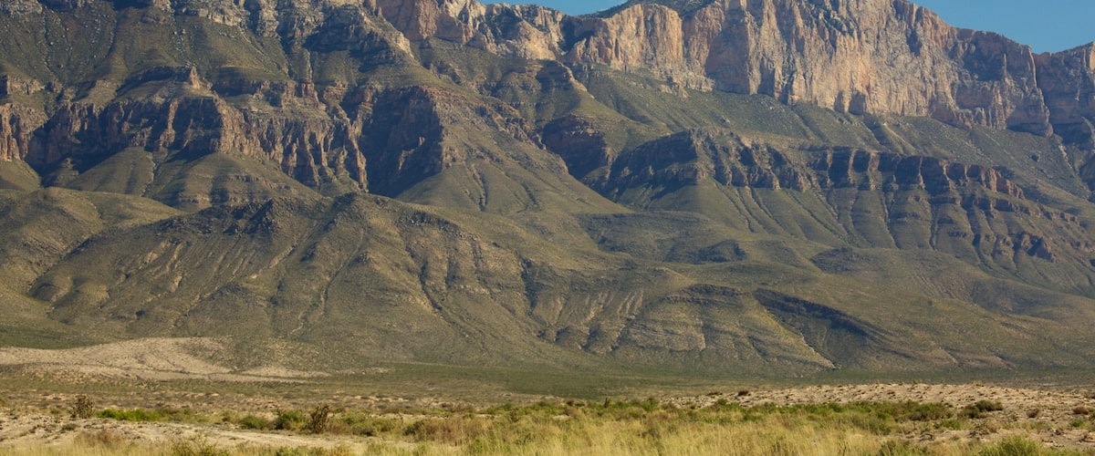 A mountainous landscape with rugged cliffs and sparse vegetation.