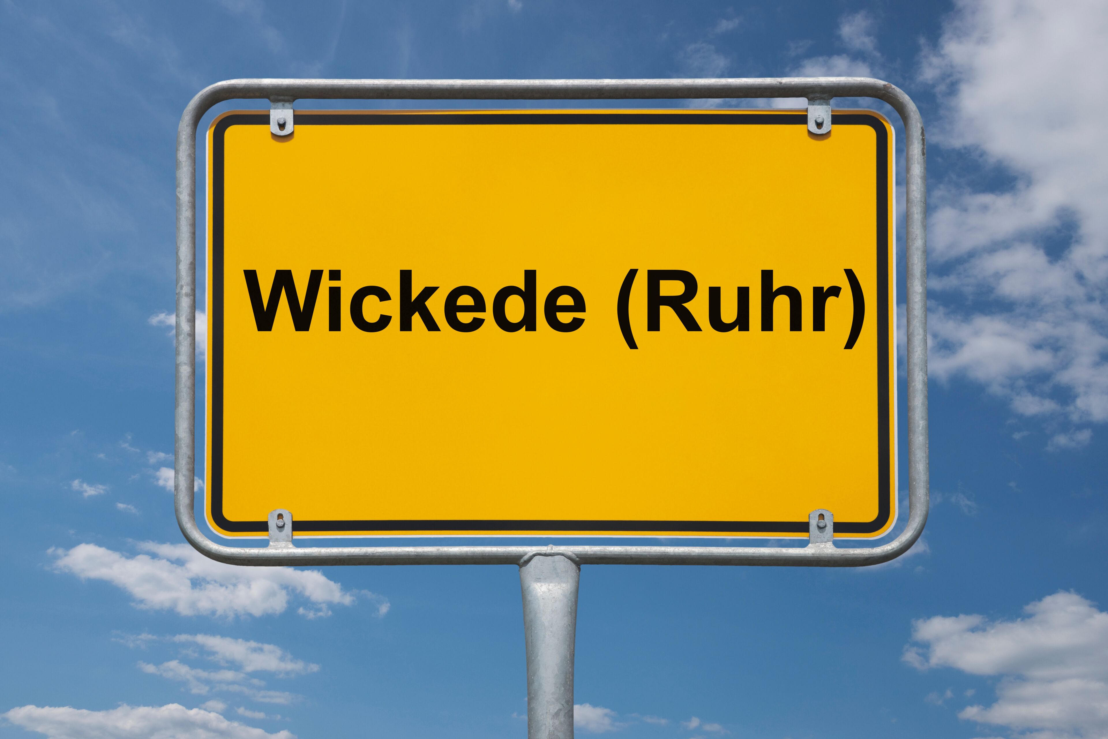 A yellow sign with the text "Wickede (Ruhr)" against a blue sky with clouds.