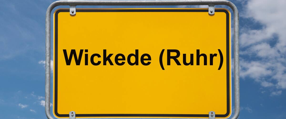 A yellow sign with the text "Wickede (Ruhr)" against a blue sky with clouds.