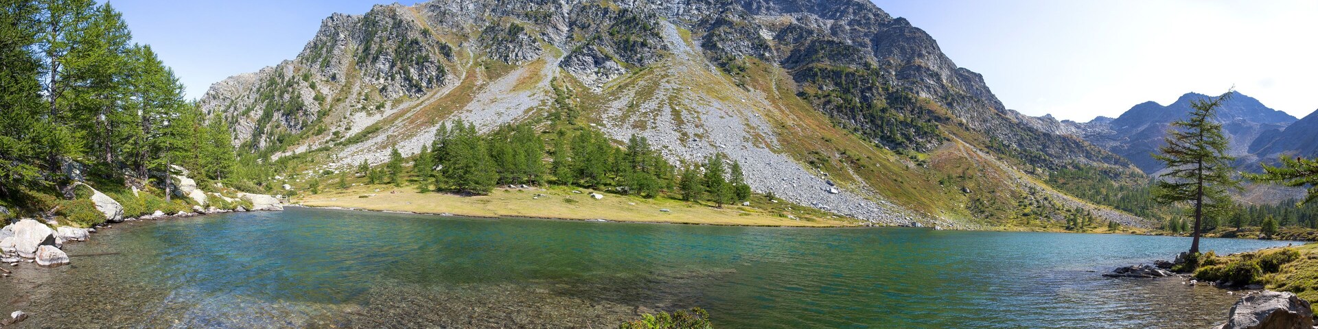 Un lago de montaña con aguas cristalinas, rodeado de terreno rocoso y vegetación escasa.