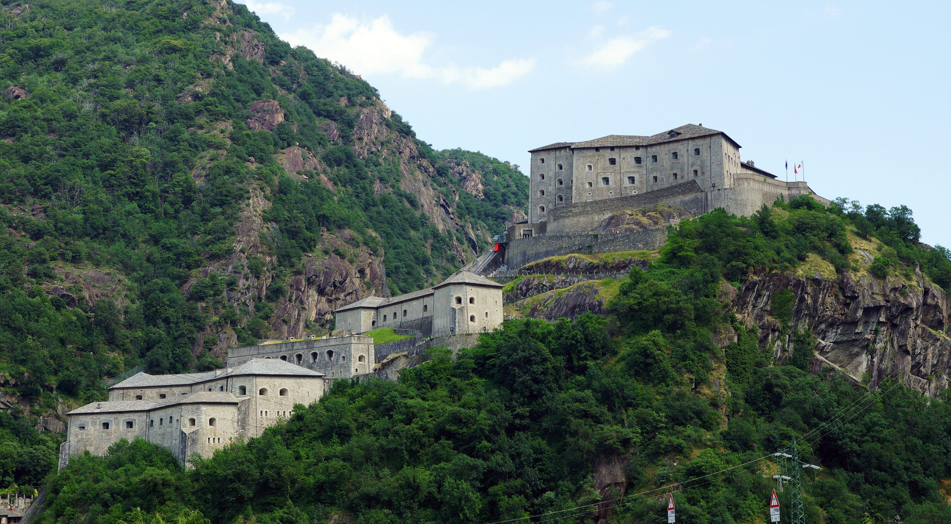 A historic fortress on a hill with surrounding lush greenery.