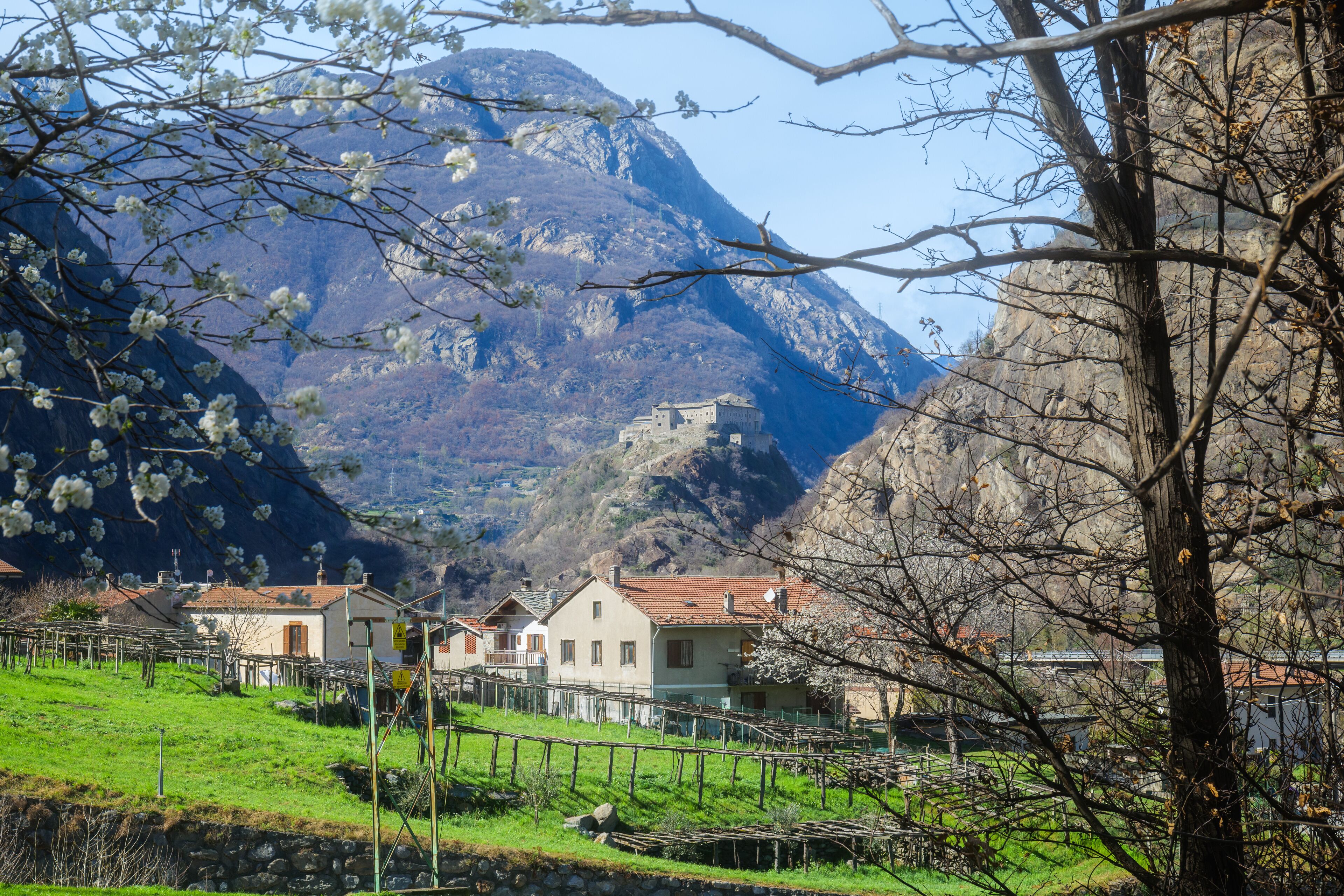 Donnas, Italy. Panoramic view of the Bard Fort from Chignas, in the municipality of Donnas. In the foreground country houses and green fields. 2023-03-25.