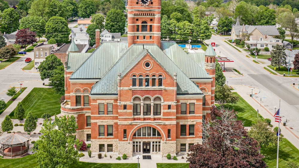 A large brick building with a clock tower, surrounded by green lawns and trees.
