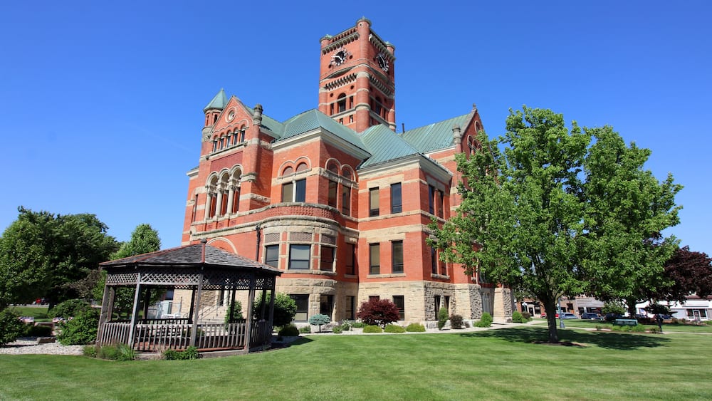 A large, historic building with a prominent tower and a gazebo in the foreground.