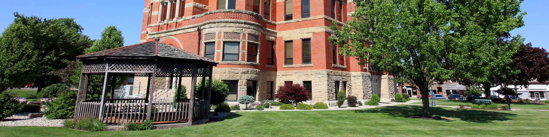 A large, historic building with a prominent tower and a gazebo in the foreground.