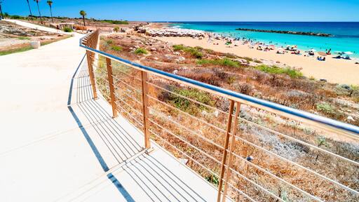 View from Paphos seaside promenade on Turquoise waters Mediterranean Sea, Venus Beach with relaxing tourists. The most beautiful beaches on holiday island Cyprus, Paphos.