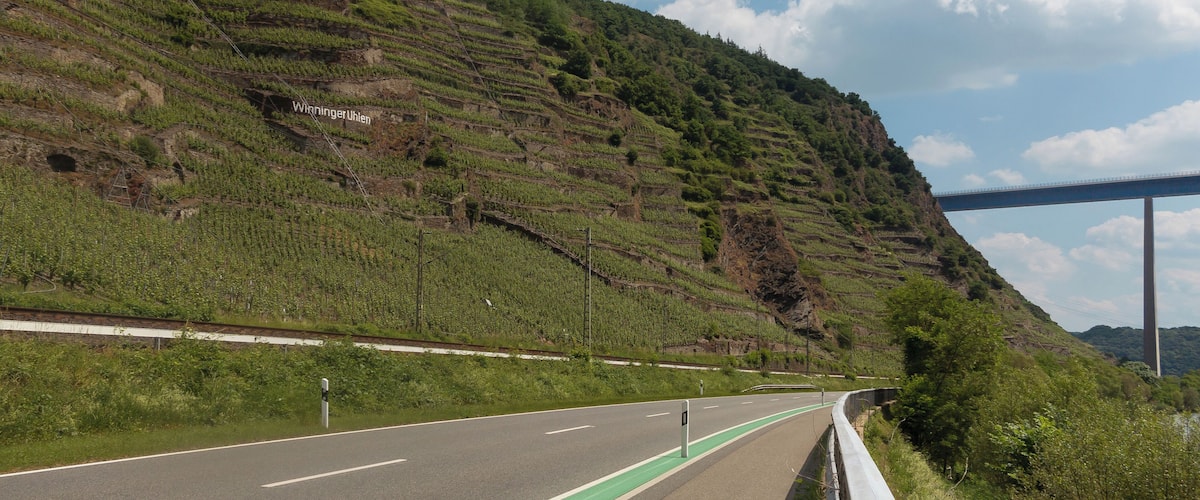A road with terraced fields and a bridge in the distance.