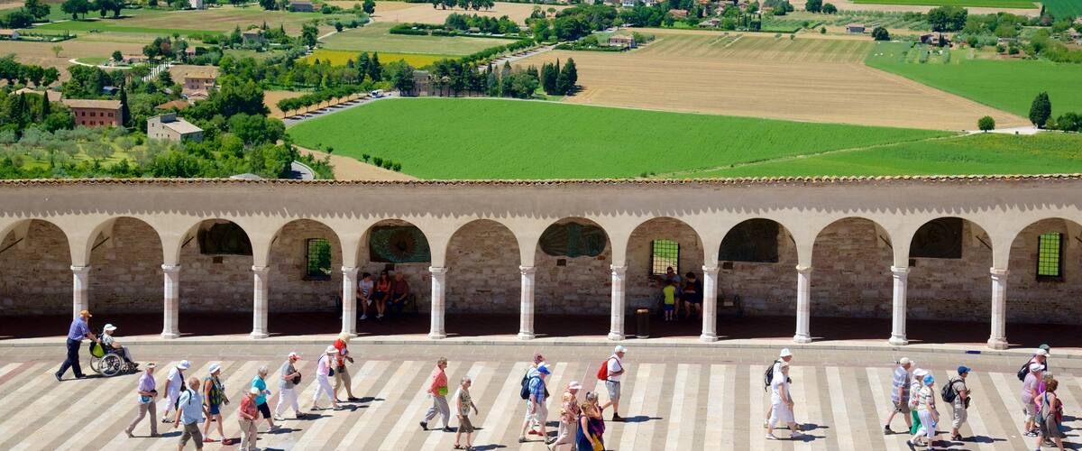 A historical square with a row of arches and people walking.