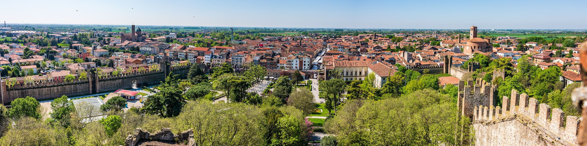 A historic cityscape with a prominent castle, dense urban area, and surrounding greenery.