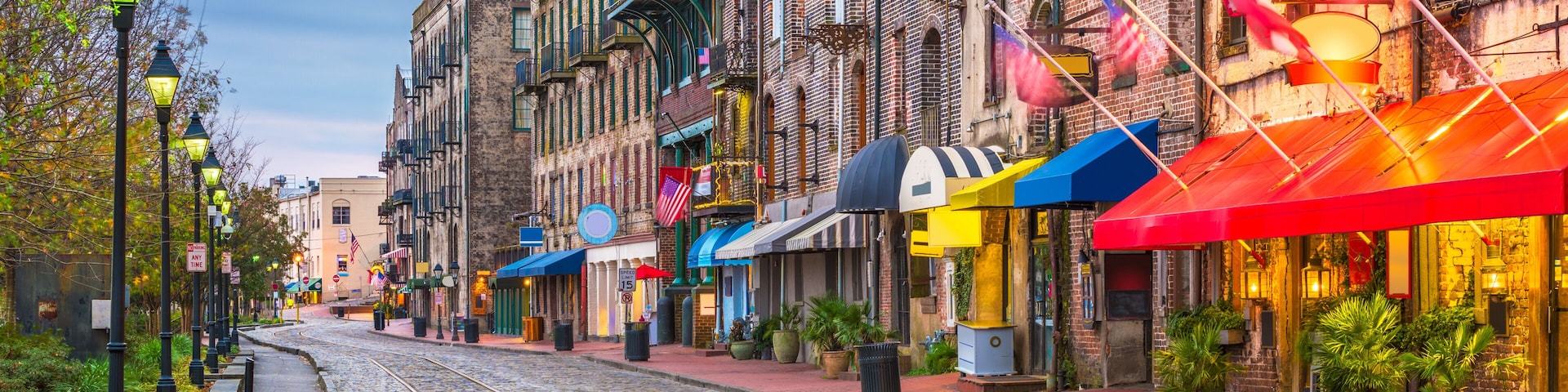 Una calle adoquinada con edificios históricos, una vía de tranvía y toldos coloridos.