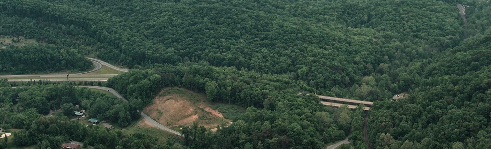 This is the view from atop the Pinnacle Overlook. it gives you a panoramic of Cumberland Gap (on your far left). From here it is easy to tell why settlers used this valley to head West. the view is sensational; You get about a 200 degree view of the western ranges of the smoky mountains. Two crazy people decided to climb over the railing and down to the edge of the cliff. A few hundred feet below is the small town of Cumberland.