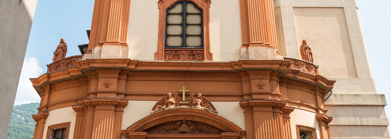 Una iglesia con una torre del reloj, fachada ornamentada y estatuas.