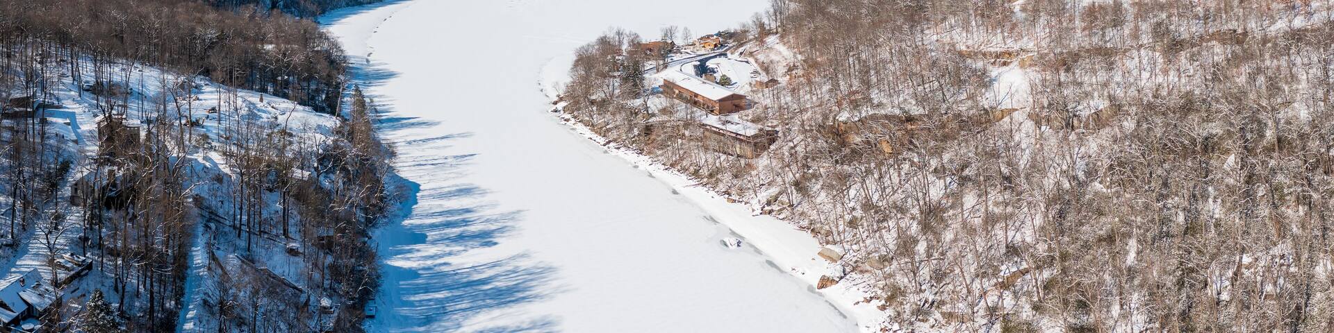 Aerial drone view of the snow-covered and frozen Cheat River flowing through the mountains towards the lake near Morgantown in West Virginia