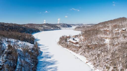 Aerial drone view of the snow-covered and frozen Cheat River flowing through the mountains towards the lake near Morgantown in West Virginia
