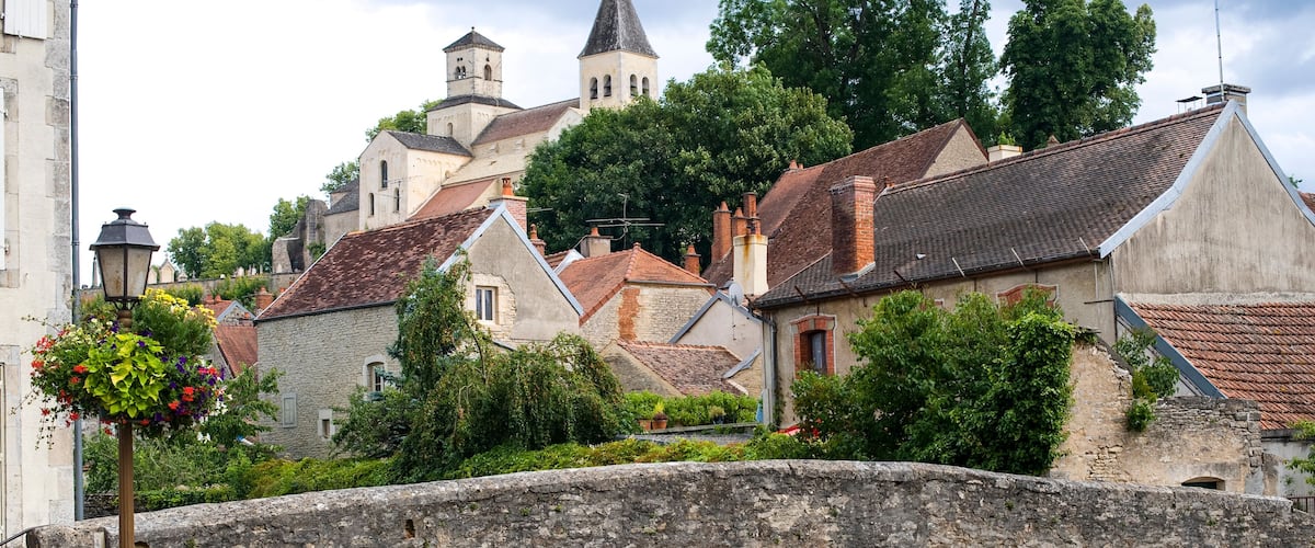 A stone bridge over a canal with historic buildings and a church in the background.