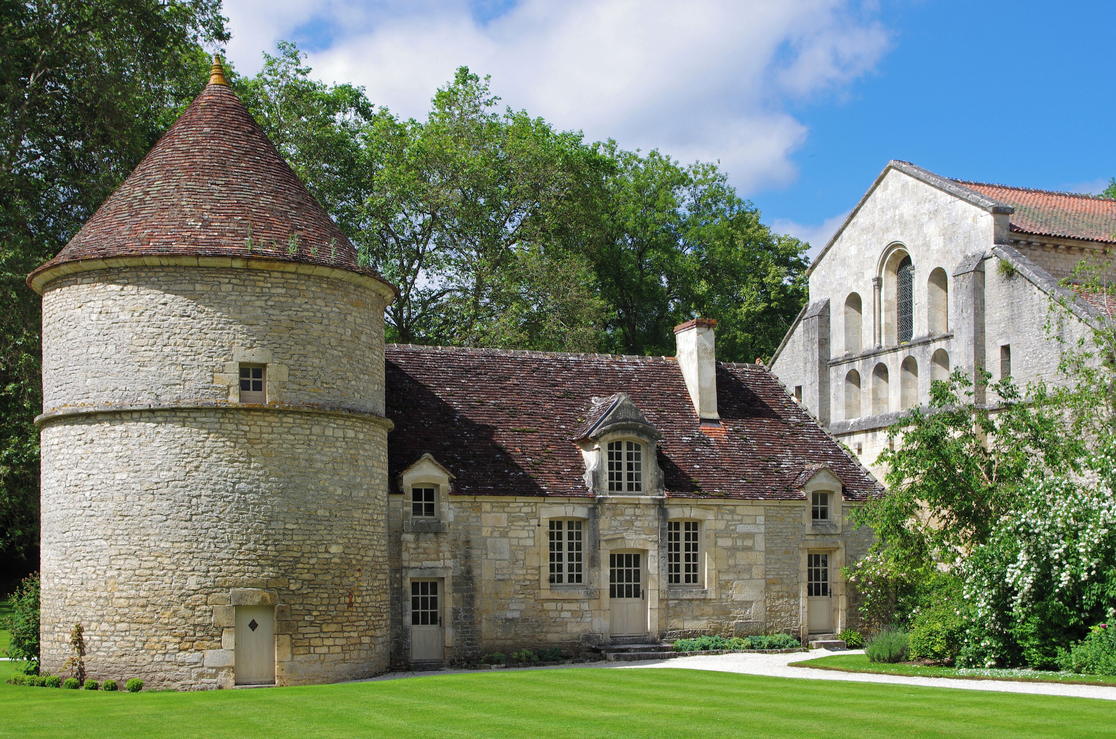 A historic stone building with a round tower and a large arched window.