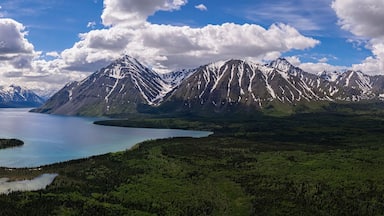 Un paisaje montañoso con un lago y zonas boscosas.