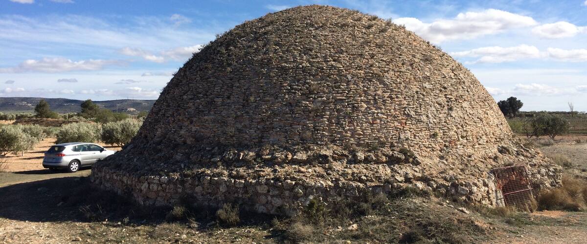 A stone dome structure in a rural setting with a clear sky.