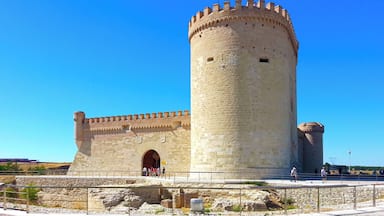 A historic stone tower with a flag, a large arched entrance, and a surrounding paved area.