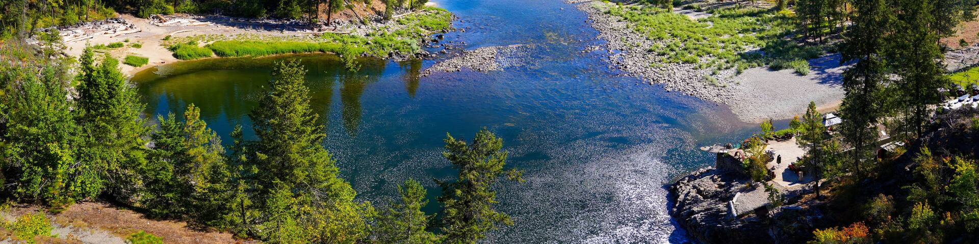 A river winding through a forested valley with mountains in the background.