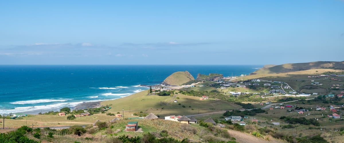 A coastal town with houses, a hill, and the ocean.