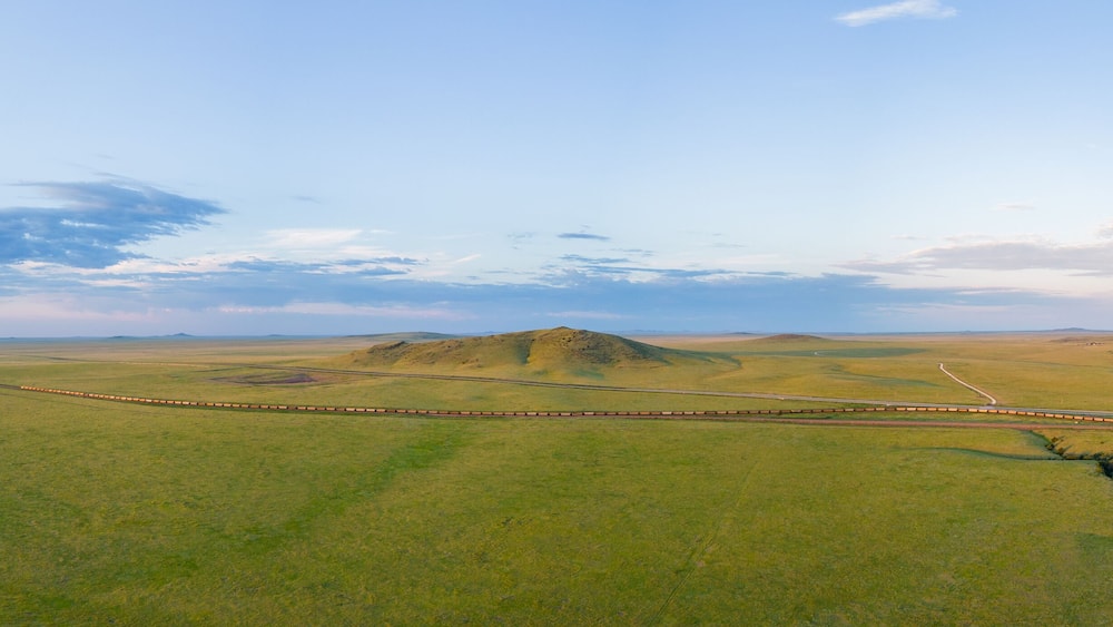 A train track winding through a green valley with hills in the background.