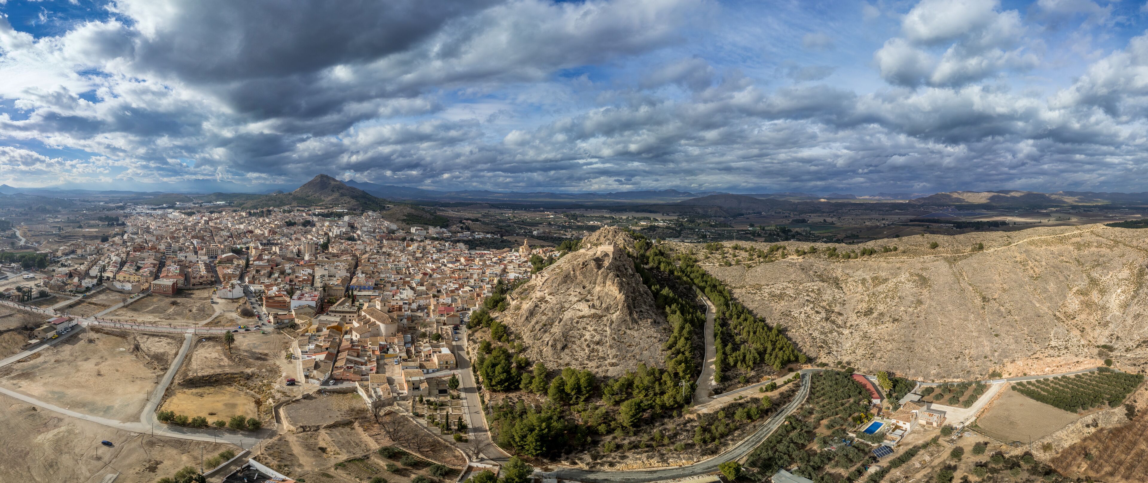 A cityscape with a prominent hill and a mountain in the background.