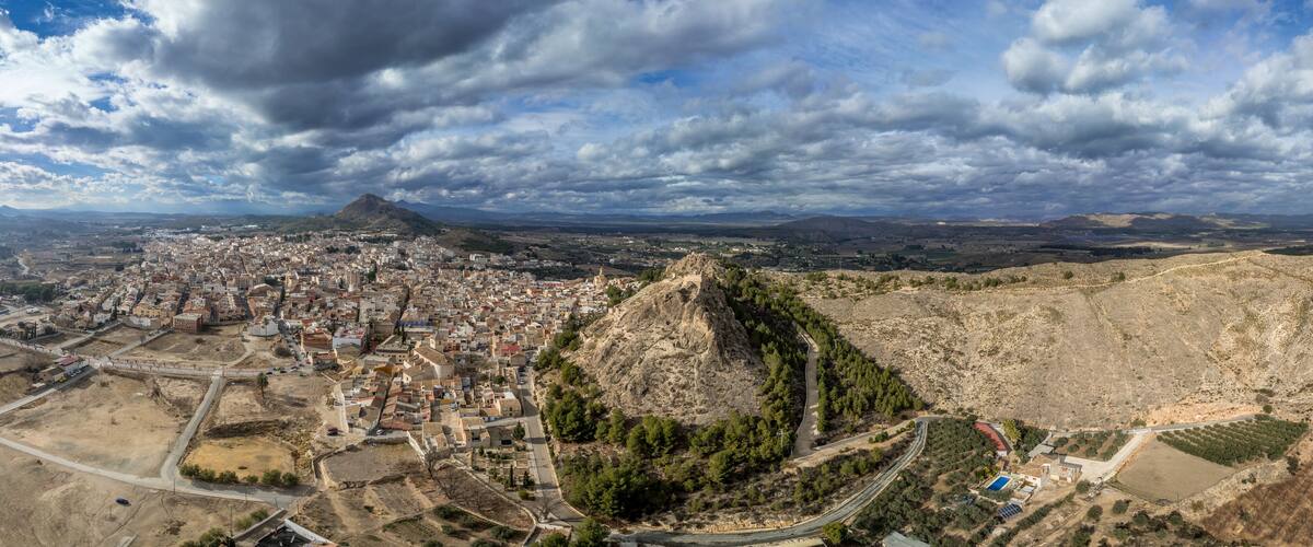 A cityscape with a prominent hill and a mountain in the background.