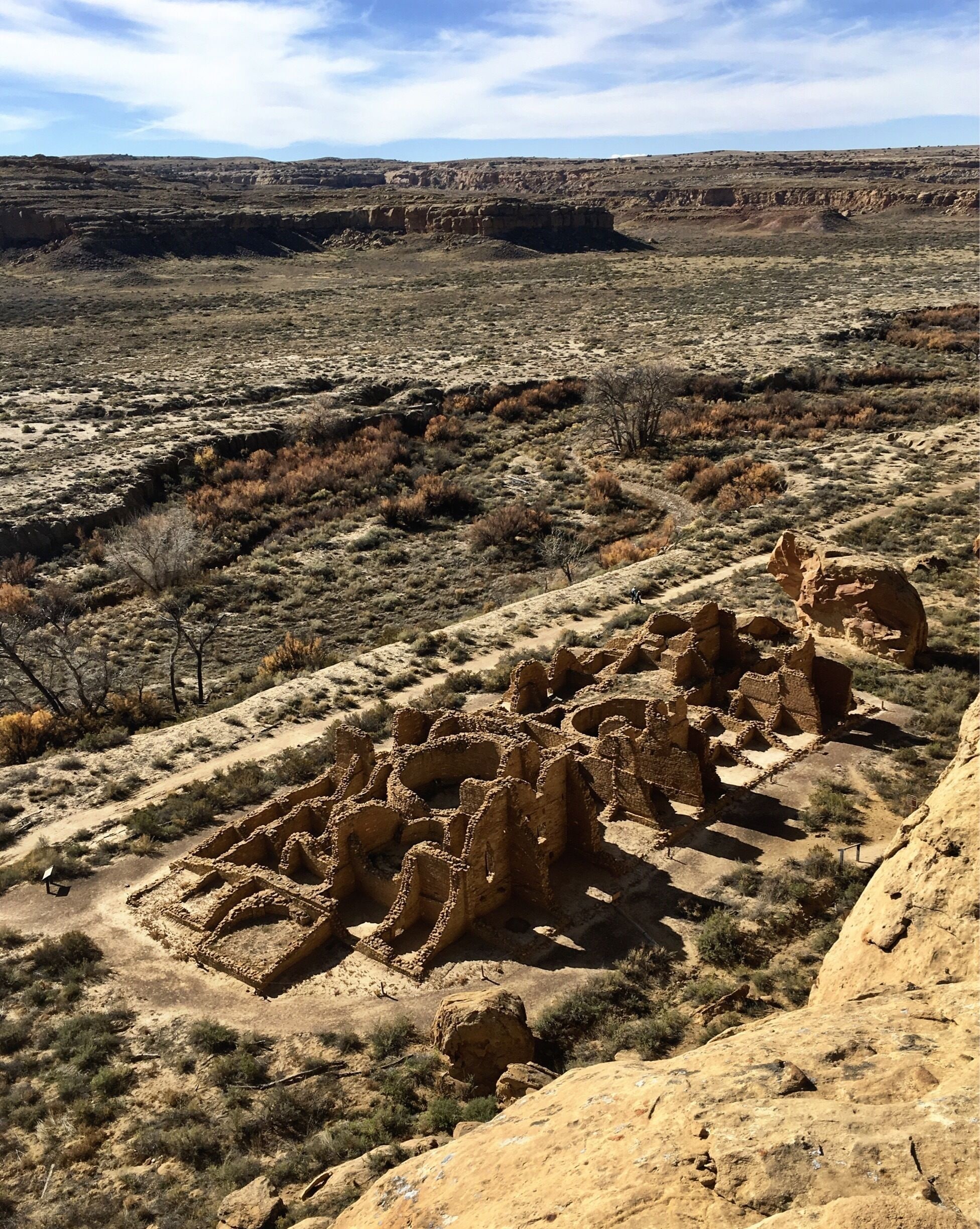 A desert landscape with ancient ruins in the foreground and a flat terrain in the background.