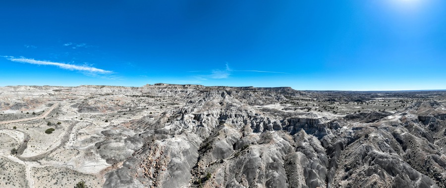 A vast, rugged landscape with layered rock formations and a clear blue sky.