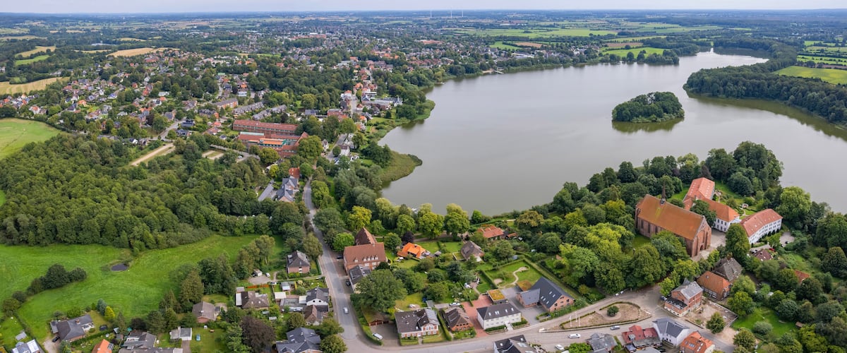 An aerial view of a town by a large lake with surrounding greenery and a church.