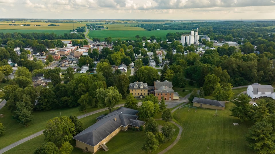 Aerial view of the town nestled among lush green trees and open fields, with the grain elevators standing tall in the distance, West Liberty, Ohio, United States.
