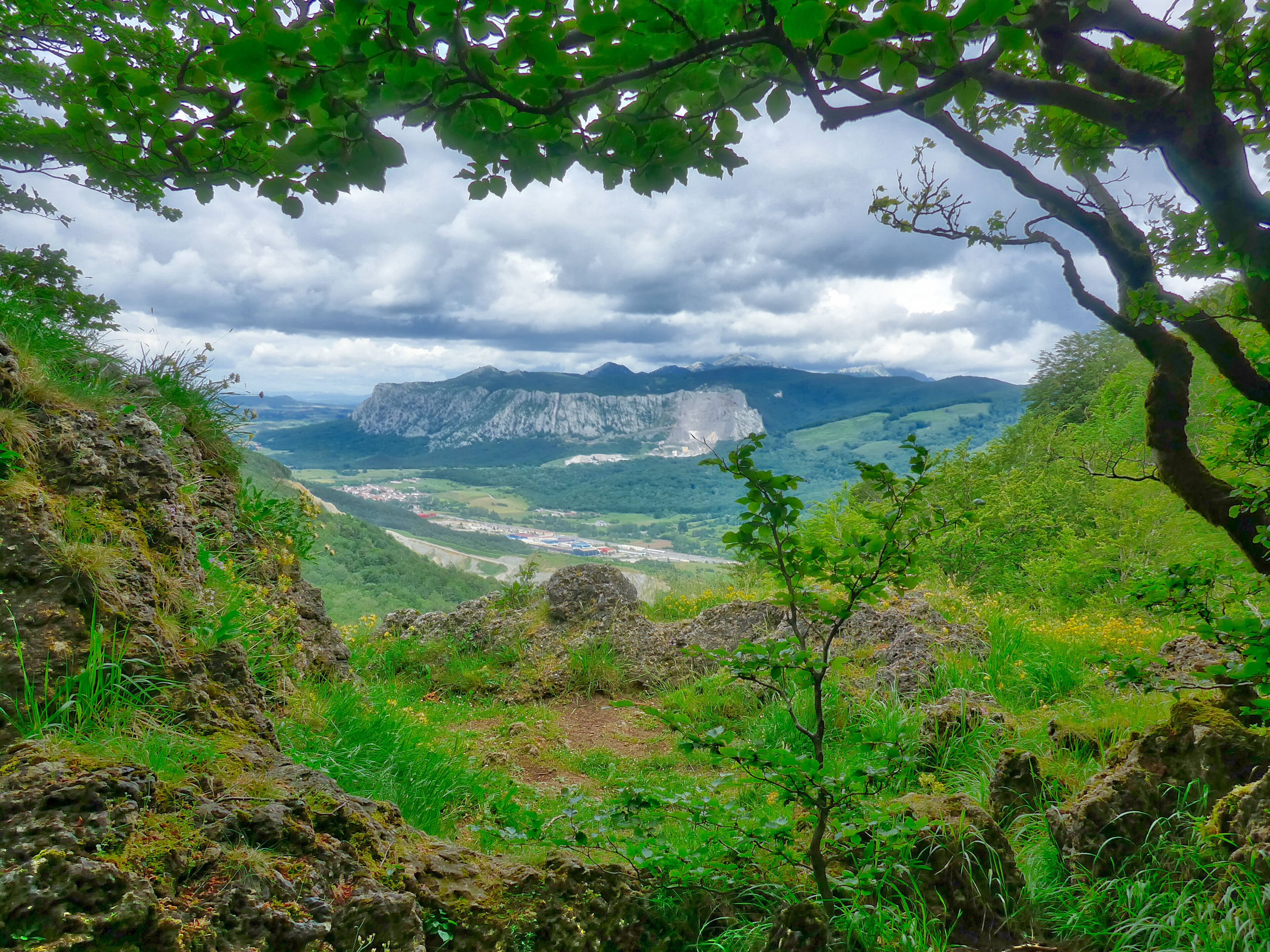 A mountainous landscape with a valley, a river, and a distant town.