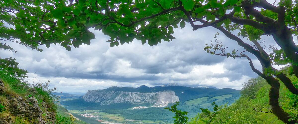 A mountainous landscape with a valley, a river, and a distant town.