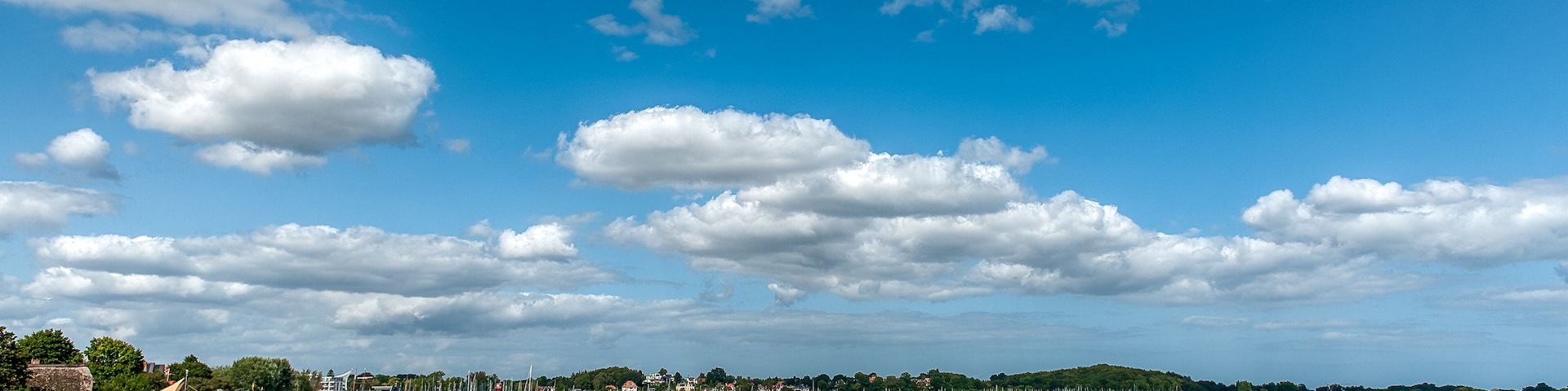 A beach with rows of numbered beach chairs and a calm sea under a partly cloudy sky.