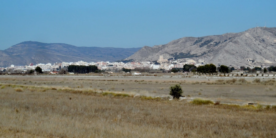 Paisatge urbà amb un turó destacat i una construcció que recorda un castell al fons.