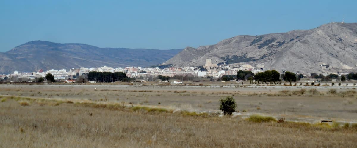 A cityscape with a prominent hill and a castle-like structure in the background.