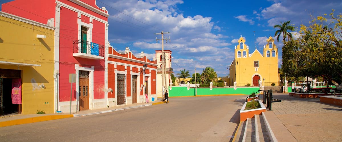 A street with colorful buildings, a church, and a clear blue sky.