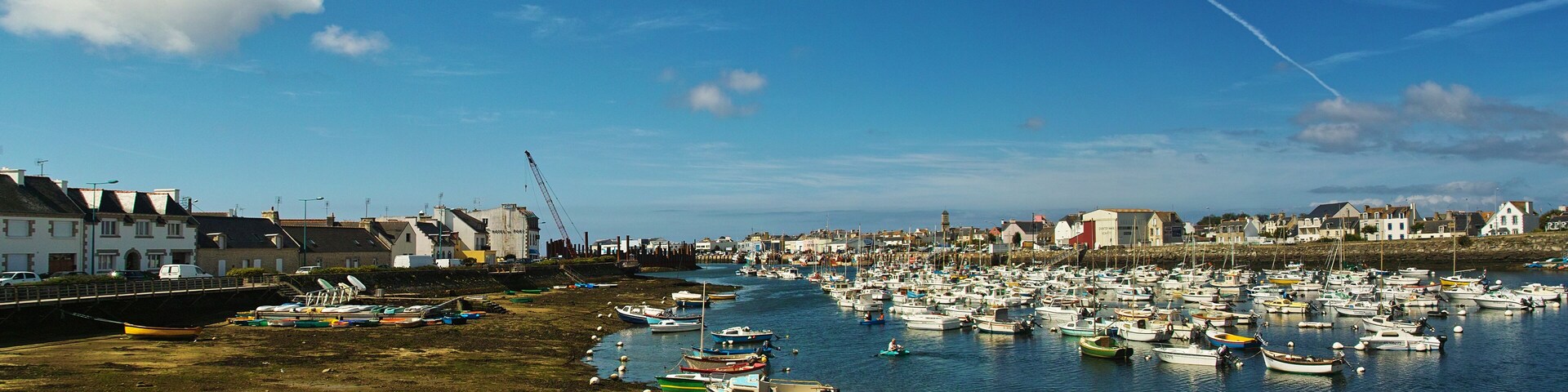 A harbor filled with boats, a sandy beach, and buildings along the shore.