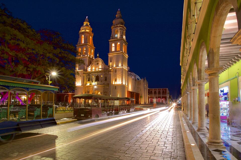 Una catedral històrica amb dues torres, un carrer empedrat i una línia de tram.