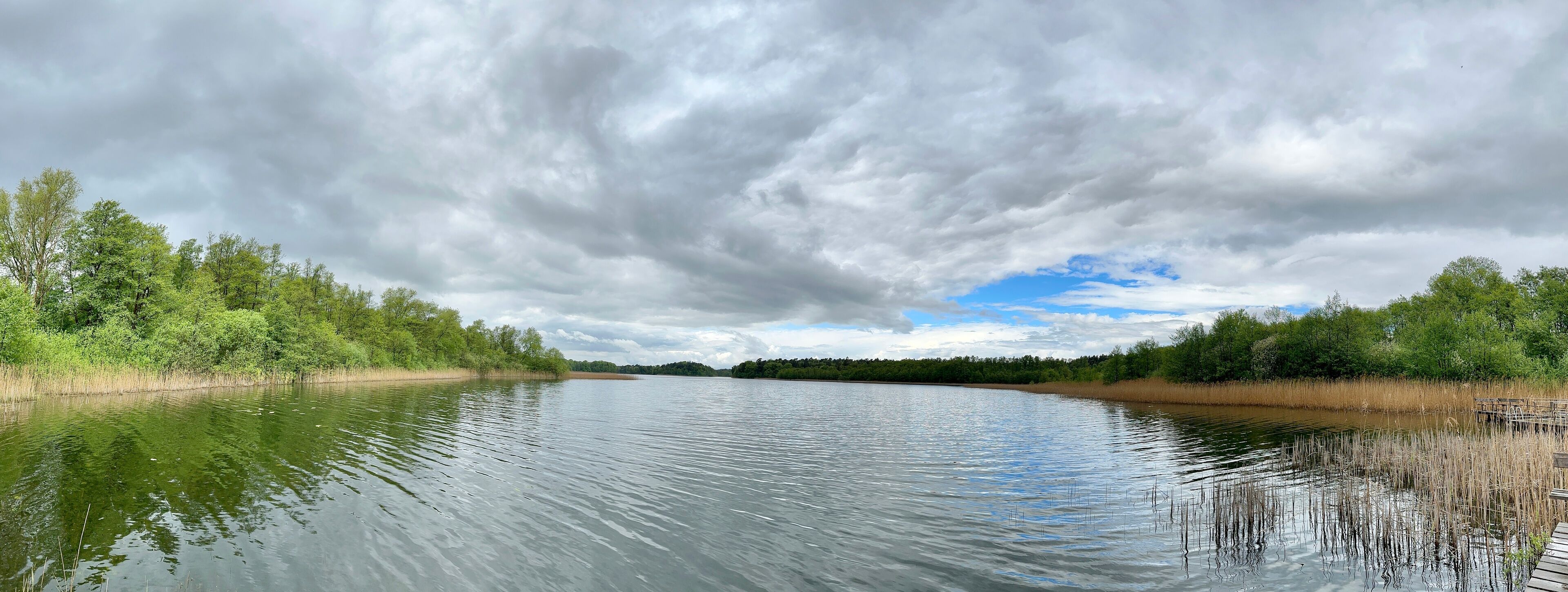 A calm river with dense greenery on both sides and a cloudy sky.