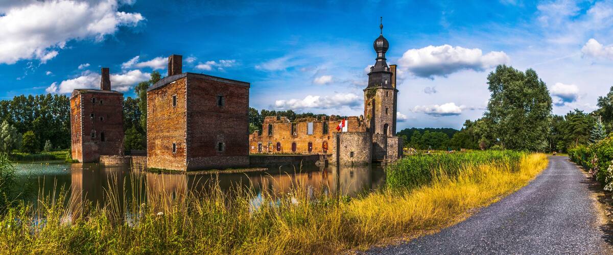 A historic building complex with a tower and a river in the foreground.