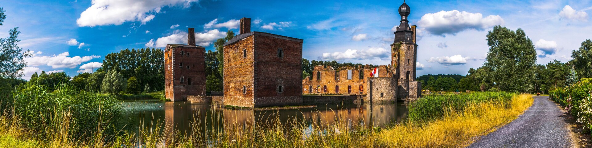 A historic building complex with a tower and a river in the foreground.